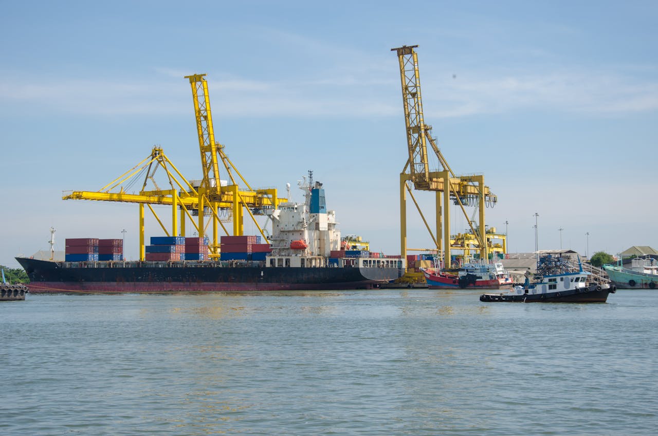 A cargo ship docked at an industrial port with cranes and containers at a bustling harbor.